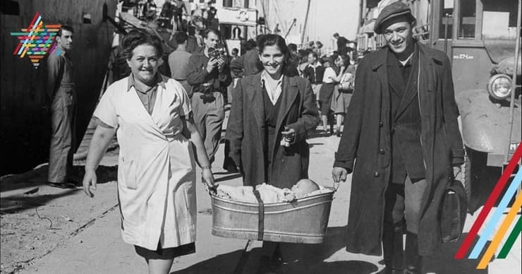 משפחת עולים חדשים מאירופה נושאים את תינוקם בתוך ''פיילה'', לאחר רדתם מהאונייה בנמל חיפה 1948