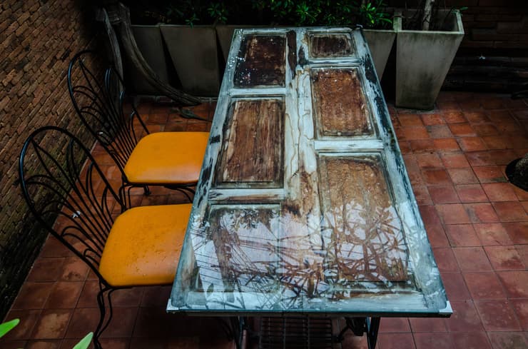 שולחן לגינה העשוי מדלת ישנה שחופתה בחיפוי זכוכית. 