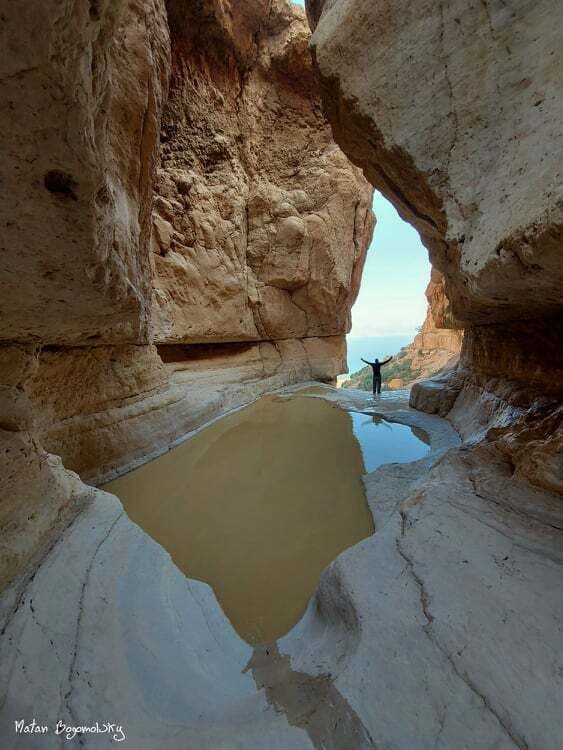 בריכת מים בין סלעי ענק ונוף לים המלח בגב חלון