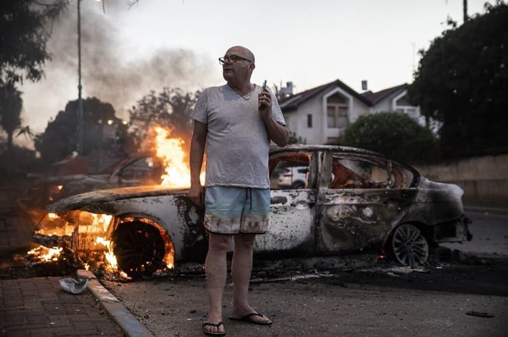 ג'ייקוב סימונה עומד ליד מכוניתו, שהועלתה באש במהלך המהומות שהתחוללו בעיר לוד בין תושביה היהודים והערבים. לוד, 11 במאי, 2021