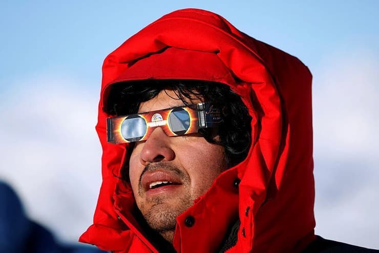 אדם עם משקפיים מיוחדות צופה בליקוי באנטארקטיקה