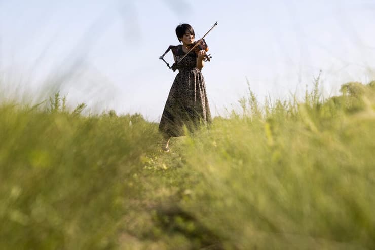 תמונות השנה של AFP שנת 2021 מוזיקאית יפנית מנאמי איטו אחות ושחיינית לשעבר מנגנת כינור בזרוע תותבת 28 אוגוסט
