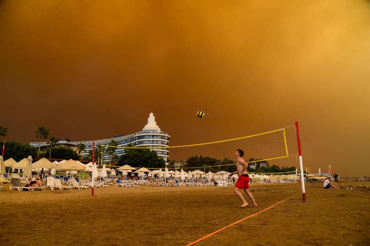 תמונות השנה של AFP שנת 2021 משחקים כדורעף באתר נופש ב דרום טורקיה בזמן שריפות 29 יולי
