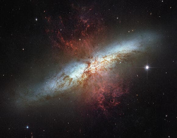 בגלקסיית M82 קצב היווצרות הכוכבים גבוה פי עשרה מאשר בשאר היקום. טלסקופ וב אמור לראות דרך ענני הגז, שנראים כאן בצילום של טלסקופ האבל