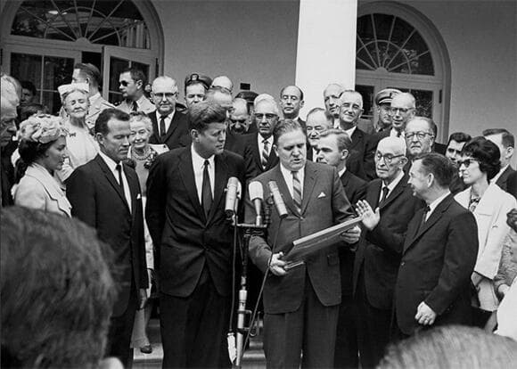 זכה להנצחה בשם הטלסקופ, למרות המחלוקת. ג'יימס וב (במרכז) מקבל אות הוקרה מהנשיא ג'ון קנדי