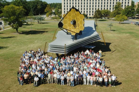 החללית הלא מאוישת הגדולה ביותר. עובדים במיזם הטלסקופ על רקע דגם בגודל מציאות של טלסקופ ג'יימס וב, במרכז גודארד של נאס"א