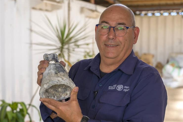 ראש היחידה לארכיאולוגיה ימית ברשות העתיקות, יעקב שרביט, מחזיק פעמון  .שנמצא בים