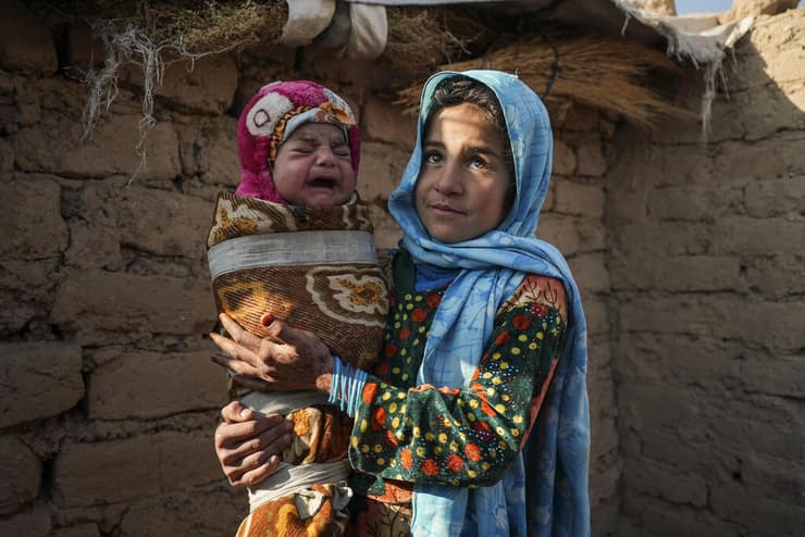 קאנדי גול מחזיקה את אחיה הקטן יישוב לעקורים אפגניסטן הורים מוכרים את הילדים
