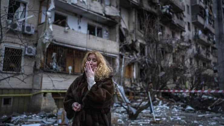 אישה לצד הריסות ביתה שנפגע במתקפת טילים בקייב, אוקראינה