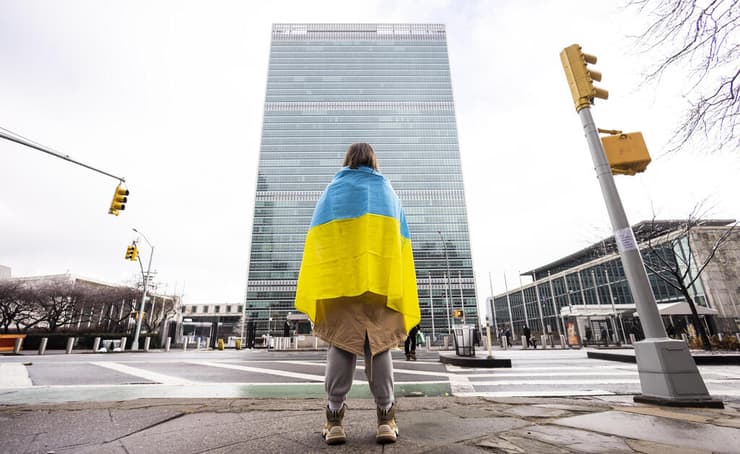 אישה עם דגל אוקראינה עומדת מול מטה האו"ם בניו יורק