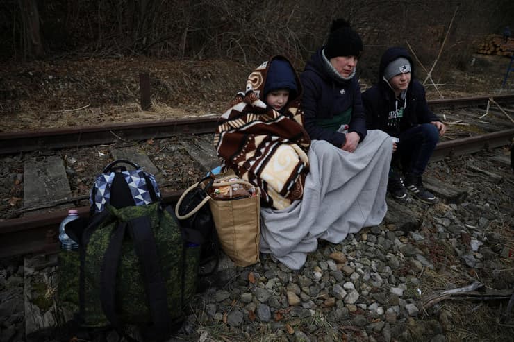 פולין פליטים אוקראינים יושבים על פסי ה רכבת  אחרי חציית הגבול ל פולין  משבר אוקראינה רוסיה מלחמה 