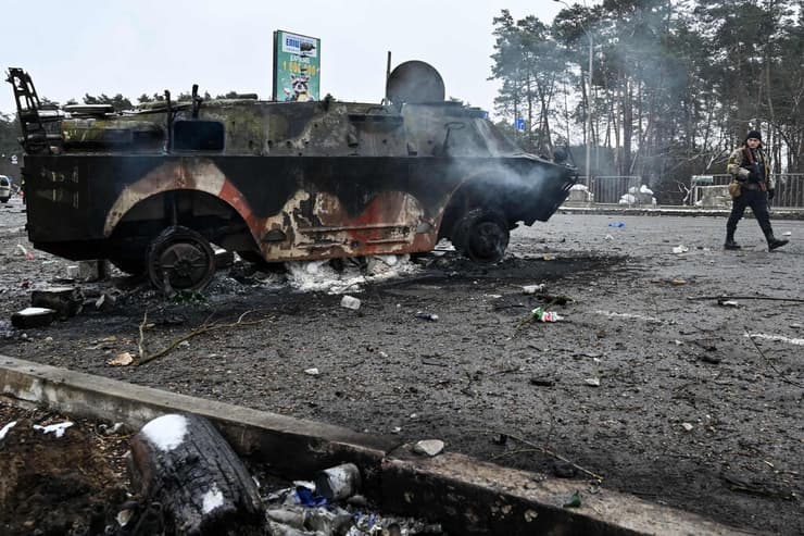  ברובארי אוקראינה אדם חמוש חולף על פני נגמש (APC) BTR-4 שרוף ב מחסום ב עיר ברובארי מחוץ ל קייב 