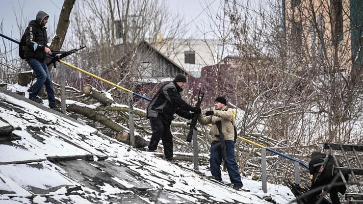 חברי יחידת הגנה אזרחית אוקראינית מעבירים רובי סער חדשים ל צד הנגדי של גשר מפוצץ 