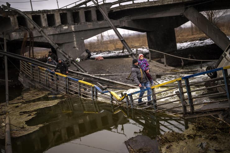איש צבא מתנדב עוזר לילדה ומשפחתה לחצות גשר שקרס באזור קייב