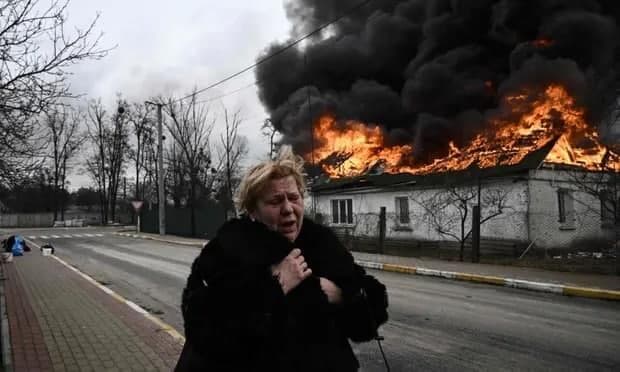 אישה עומדת מחוץ לבית בוער אחרי שהופצץ באירפין, אוקראינה