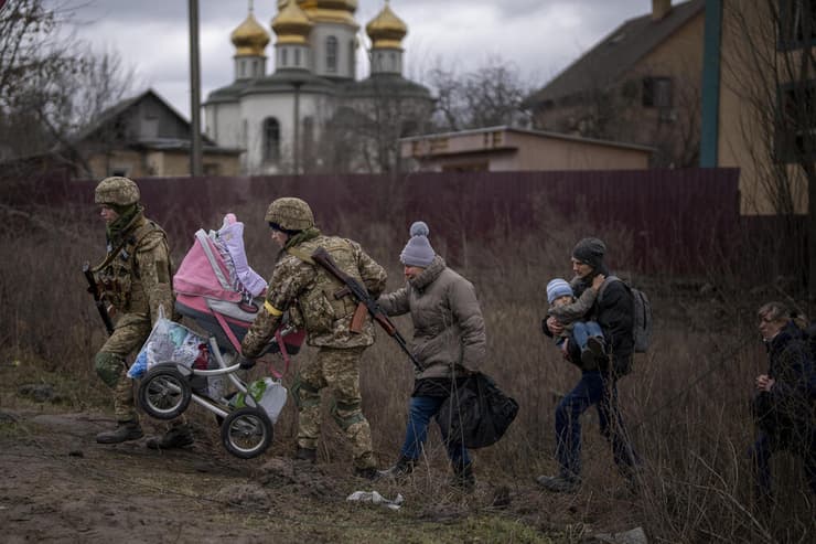 חיילים אוקראינים עוזרים למשפחה שעוזבת את העיר לעבור בשטח