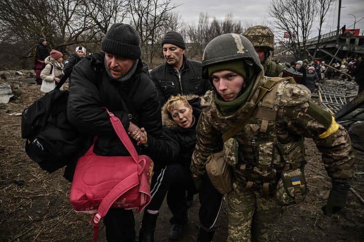 חיילים של צבא אוקראינה מסייעים למשפחה של פליטים לחצות את נהר אירפין 