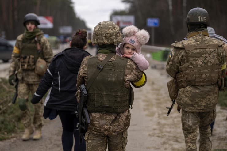 חייל של צבא אוקראינה נושא ילד ומסייע למשפחה של פליטים פליט לחצות את נהר אירפין סמוך ל קייב מלחמה עם רוסיה