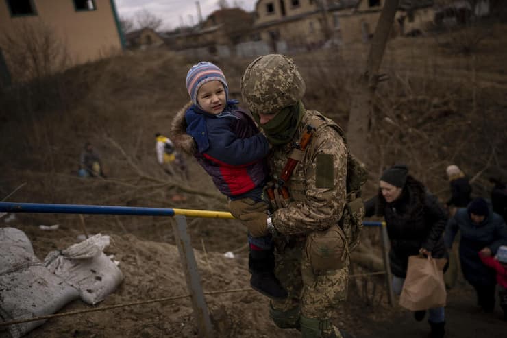 חייל אוקראיני עוזר ל ילד לחצות את נהר אירפין סמוך ל קייב אוקראינה מלחמה באירופה משבר