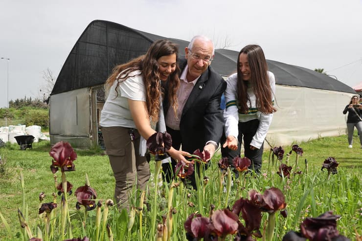 הנשיא לשעבר בוחן פרחים יחד עם תלמידות