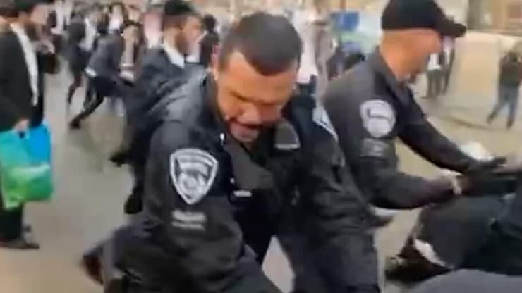 שוטר מצמיד ראש של מפגים לכביש בהפגנת החרדים