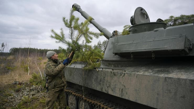 חייל של צבא אוקראינה מסתיר בצמחייה תותח הוביצר עקב מלחמה עם רוסיה באזור מקאריב שבמחוז קייב