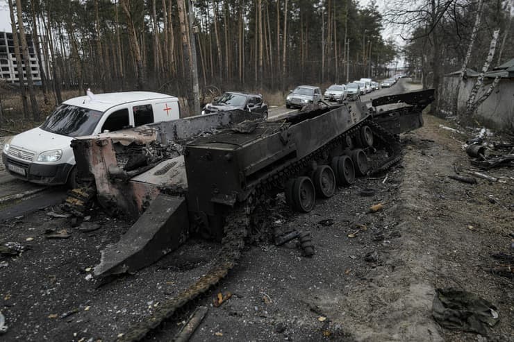 שיירת רכבים של תושבים שמתפנים מאירפין עוברת על פני טנק רוסי שרוף