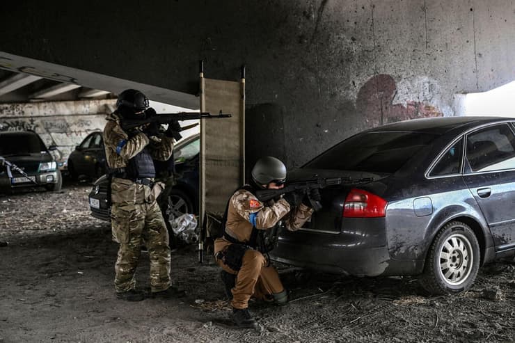 אנשי שירות אוקראינים מכוונים עם נשקם לעבר מכונית נעה מ עמדה מתחת לגשר הרוס בעיר אירפין 