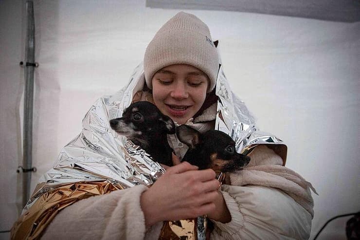 קטיה, שברחה מאוקראינה, מתחממת עם שני הכלבים שלה בפולין 