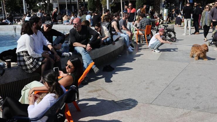 אנשים נחים בשמש בשבת בכיכר דיזינגוף