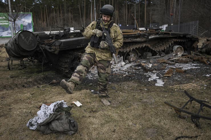 חייל אוקראיני לצד שרידי משוריין של צבא רוסיה ושק שינה שרוף ב סטויאנקה מערבית ל קייב אוקראינה מלחמה