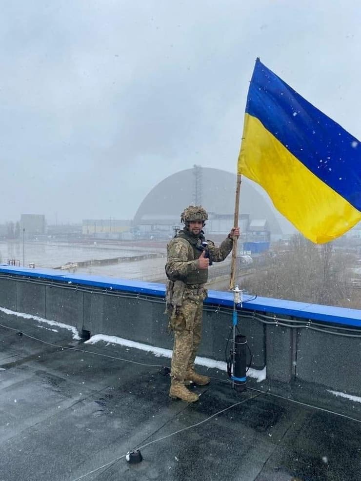חייל אוקראיני מציב דגל אוקראינה במתחם הכור בצ'רנוביל