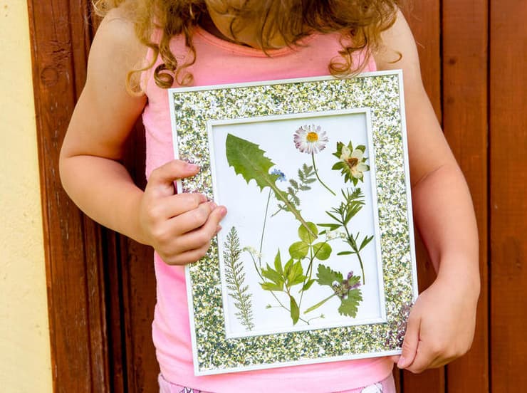 תעסוקה לילדים וחיבור לטבע: ייבוש פרחים בין דפי ספר ומסגור שלהם. 