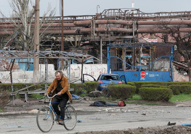 אוקראינה רוכב אופניים חולף על פני גופה ליד מפעל המתכות איליץ' מריופול מלחמה עם רוסיה