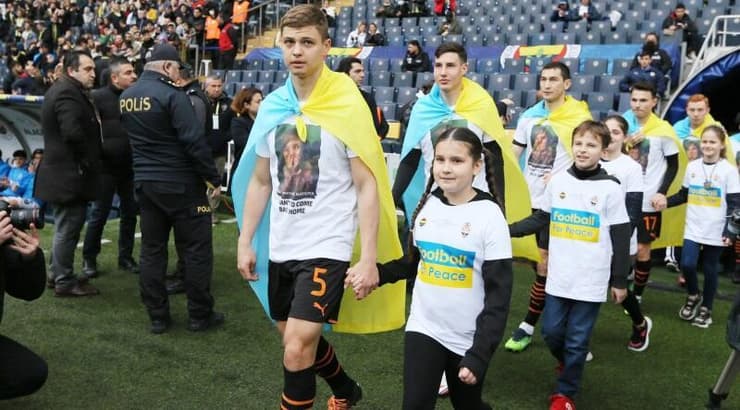 שחקני שחטאר עולים למגרש עם דגלי אוקראינה על גבם