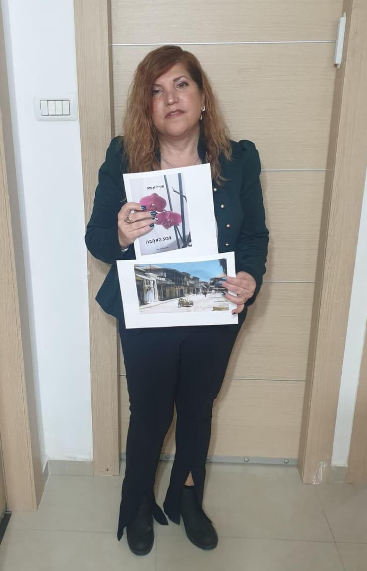 אורלי אסיה עם צילום של הבאר של סבה רחמים ועם תמונה של כריכת ספרה החדש