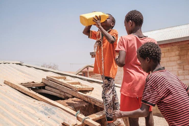 ילדים עומדים בתור לשתות מים בבור מים בכפר באתיופיה
