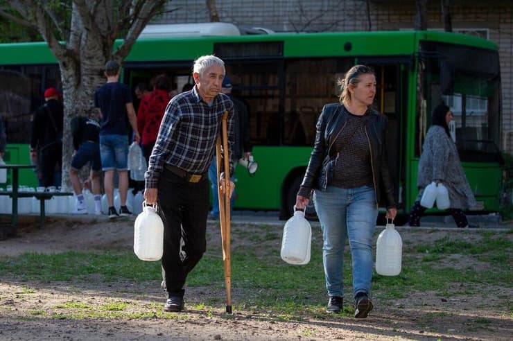 תושבי מיקולאייב אוספים בקבוקי שתייה שנשלחו מאודסה באוטובוסים על ידי פליטים