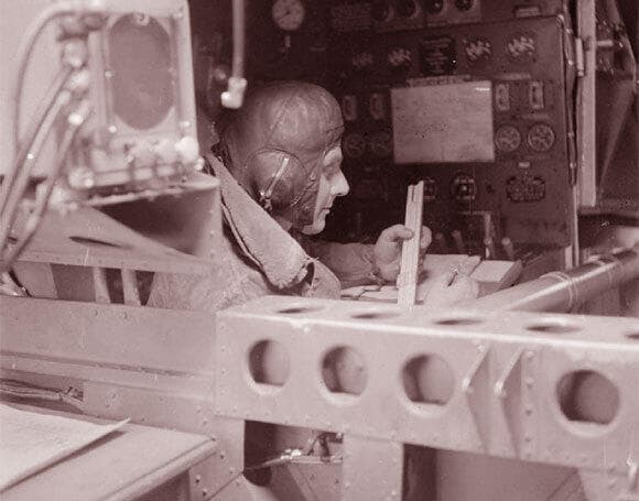 מכונאי מוטס במפציץ בריטי נעזר בסרגל חישוב כדי לחשב את צריכת הדלק של המטוס, אוקטובר 1941