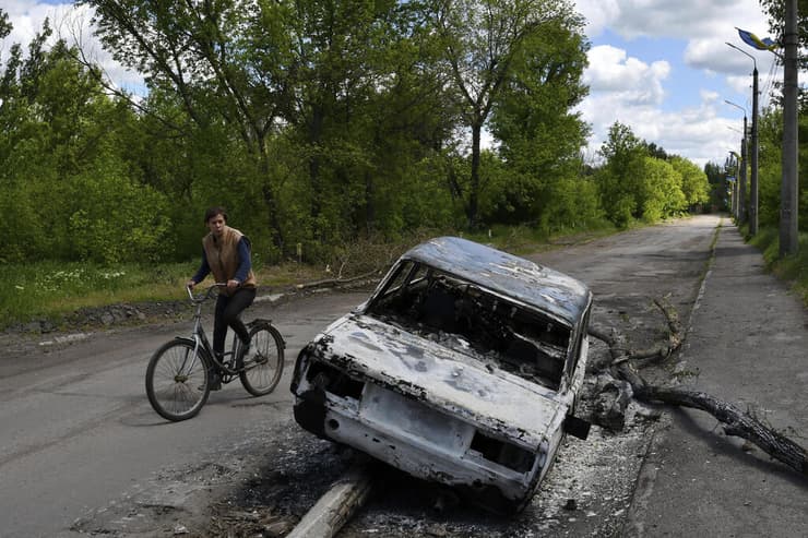 אוקראינה גבר רוכב על אופניים ליד רכב ש נשרף מחוז דונייצק מלחמה רוסיה