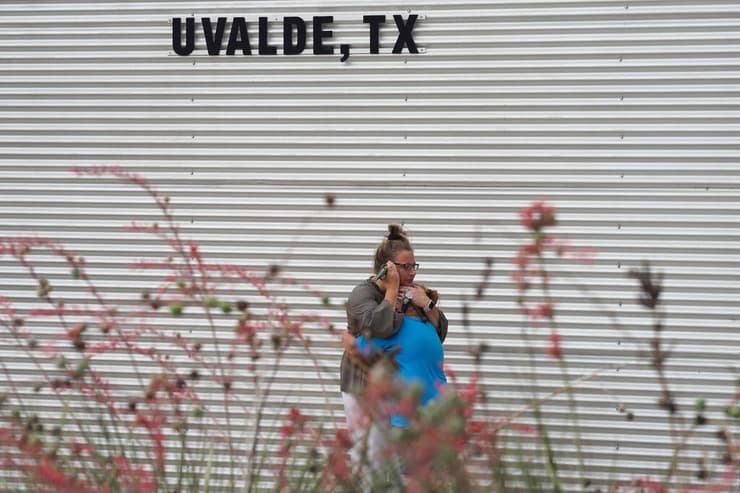 ארה"ב טקסס אישה מחבקת ילדה ליד מרכז קהילתי שבו בני משפחה מקבלים מידע על גורל יקיריהם טבח בית ספר יובלדי