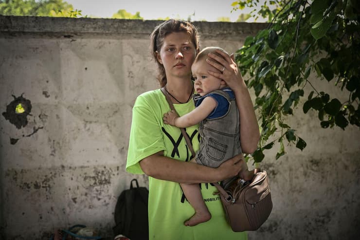 אישה ותינוק פליטים מחכים ל אוטובוס שיבריח אותם מהעיירה ליסיצ'נסק שבמחוז לוהנסק בחבל דונבאס מלחמה אוקראינה רוסיה
