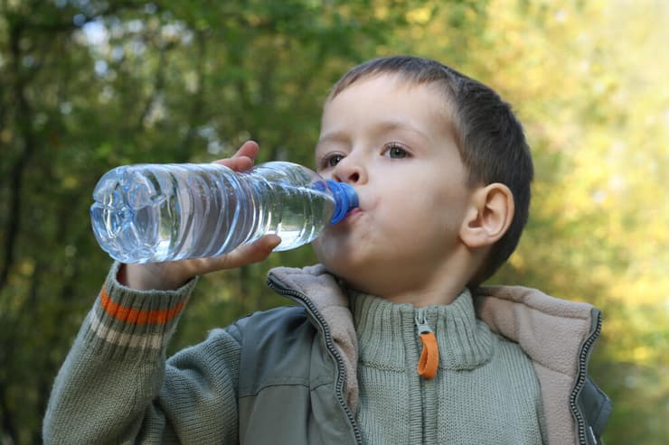 ילד שותה מים מינרלים מבקבוק