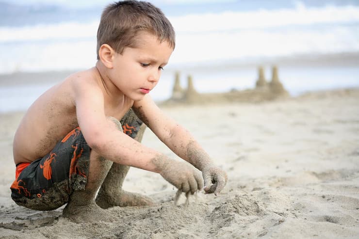 ילד משחק בחול על חוף הים