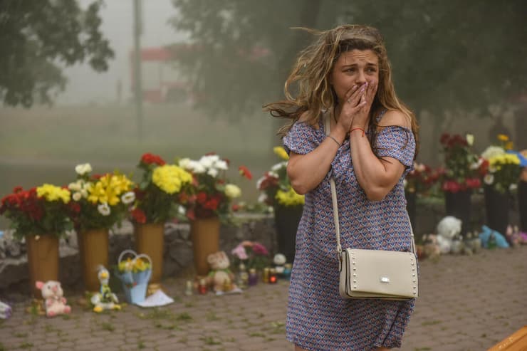 אוקראינה הריסות קניון קרמנצ'וק פגיעה של טיל רוסיה שריפה אישה בוכה ליד פרחים שהובאו למקום