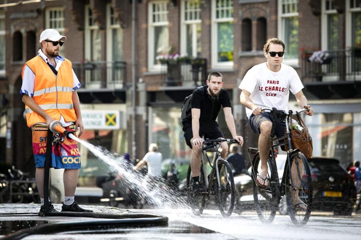 גל חום הולנד אמסטרדם עובדי עירייה מתיזים מים על גשרים כדי שהמתכת לא תימס וייתקע