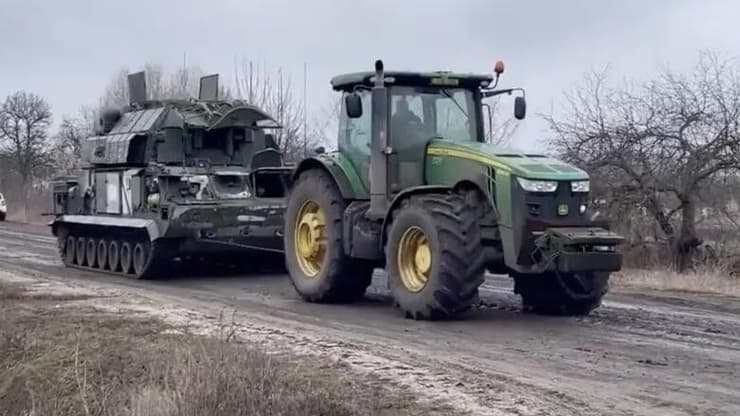 אוקראינה חקלאים גוררים עם טרקטור כלי צבאי רוסי של רוסיה