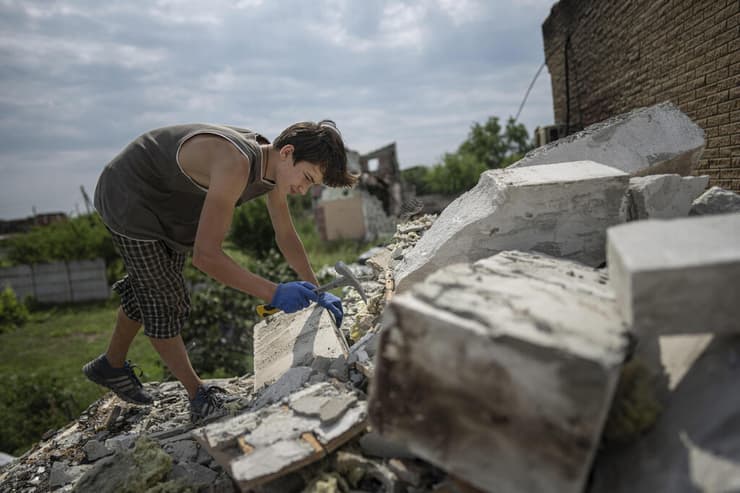 דניק ראק מסייע בפינוי הריסות מ בתים הרוסים בכפר באזור צ'רניהיב שהופגז בתחילת מלחמה אוקראינה רוסיה