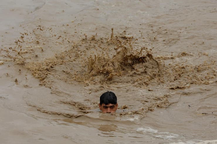 פקיסטן צעיר שוחה ב מי ה שיטפונות