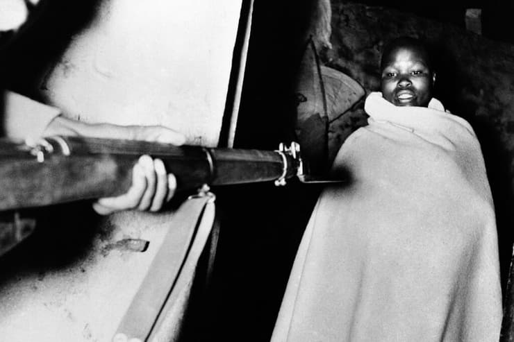 רובה מכוון לעבר חבר ב מחתרת ה מאו מאו ב קניה 1952 במסגרת דיכוי המרד על ידי שלטונות בריטניה קולוניאליזם